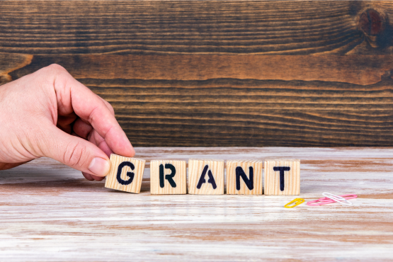 A person's hand arranging blocks to spell out the word "Grant"