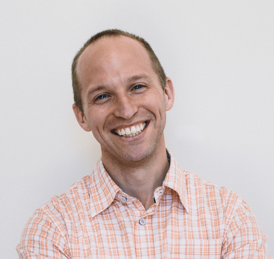 profile picture of white male with smiling face wearing orange and white checkered collared shirt on white background