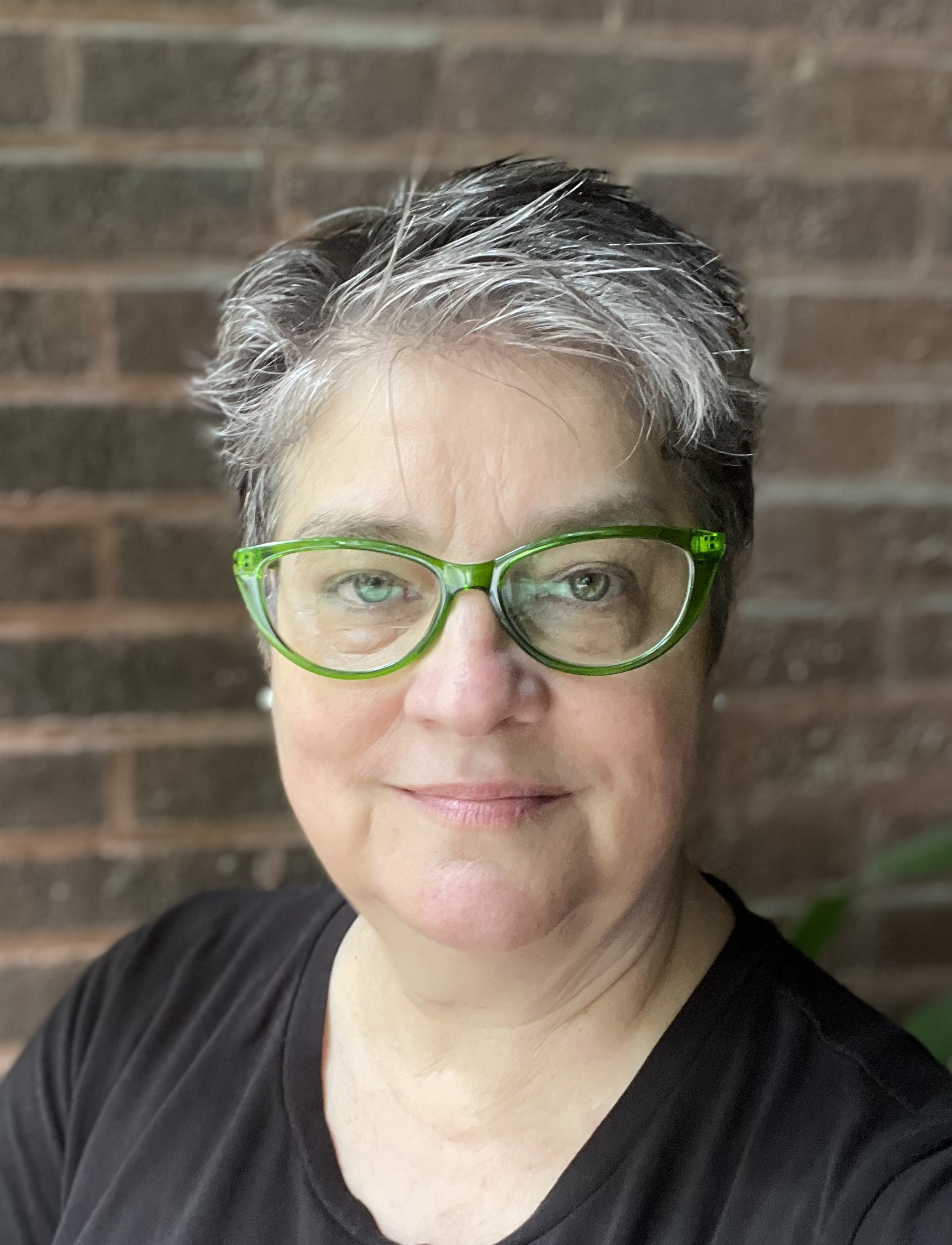 Photo of a woman with short grey hair and green glasses.