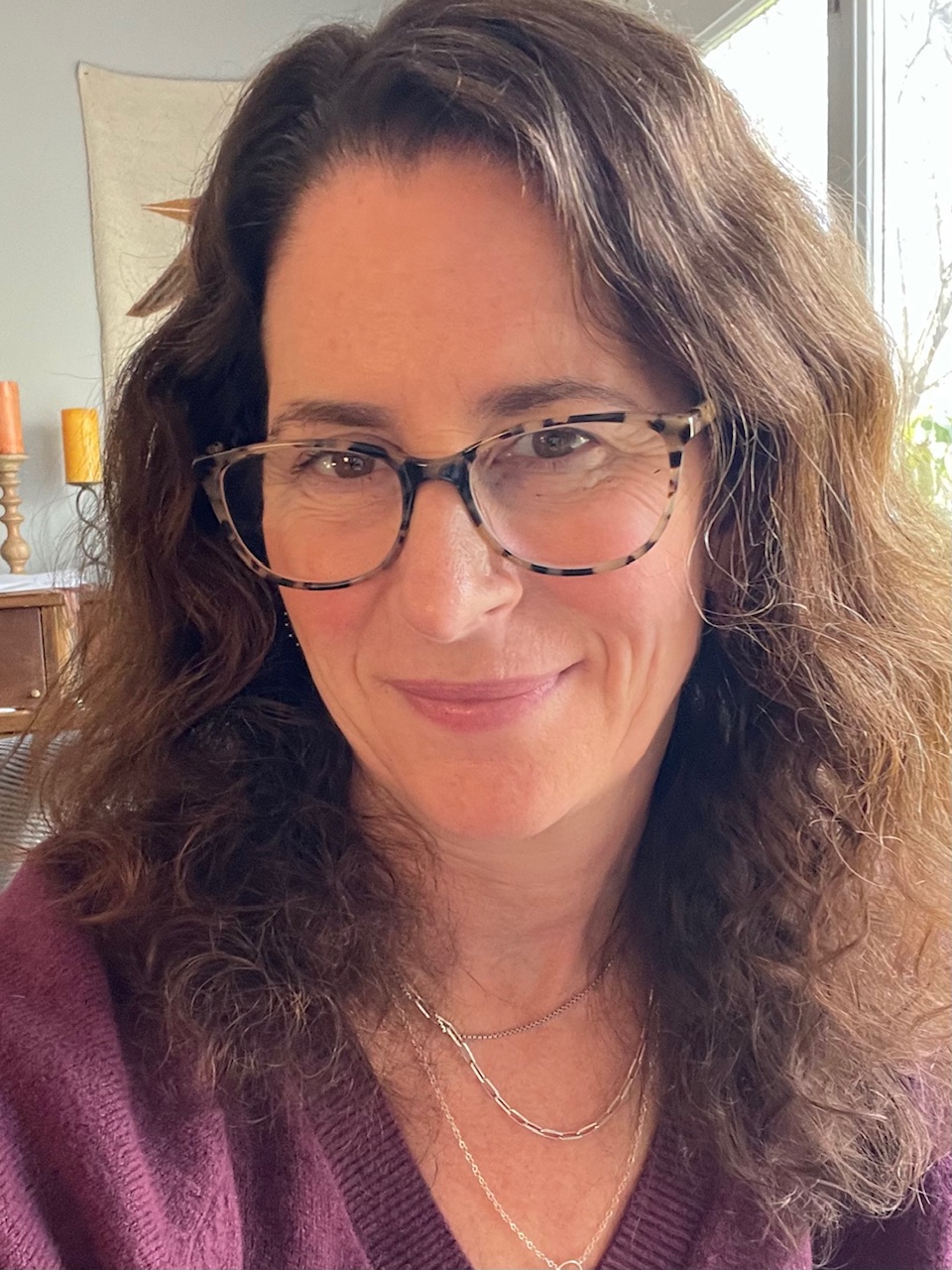 photo of Liz at her desk in a purple sweater