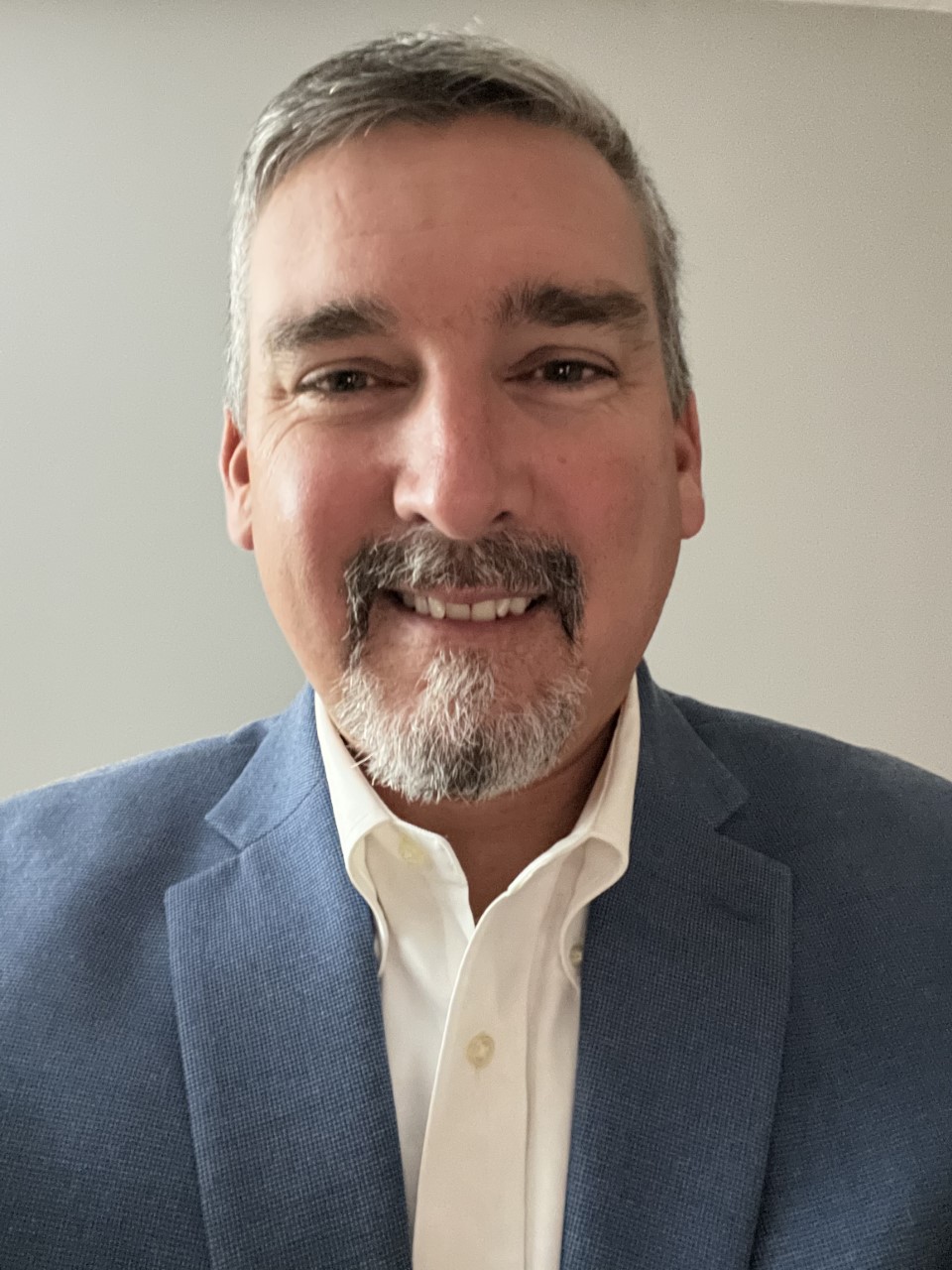 Headshot of Jamie Devlin, wearing a white button-down and blue blazer.